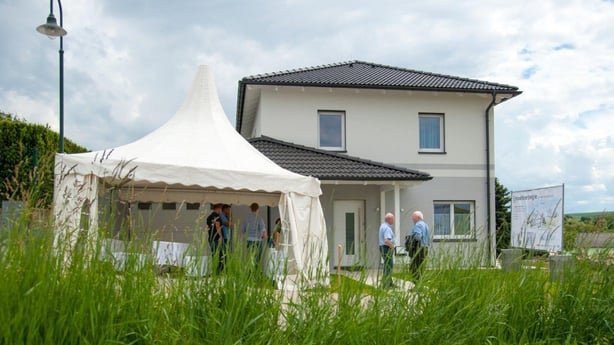 Außenansicht des Forschungsprojekts 'Haus ohne Heizung' in Göllersdorf. Das moderne, weiße Einfamilienhaus wird bei einer Veranstaltung präsentiert.