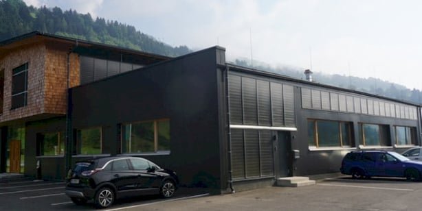 Außenansicht der Wohnmanufaktur Taxenbach. Das moderne Plus-Energie-Gebäude kombiniert eine dunkle Fassade mit Holzelementen.