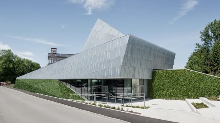 Außenansicht der nachhaltigen Kirche und des Gemeindezentrums Rif. Das moderne Gebäude hat eine skulpturale Architektur mit Metallfassade und begrünten Wänden.