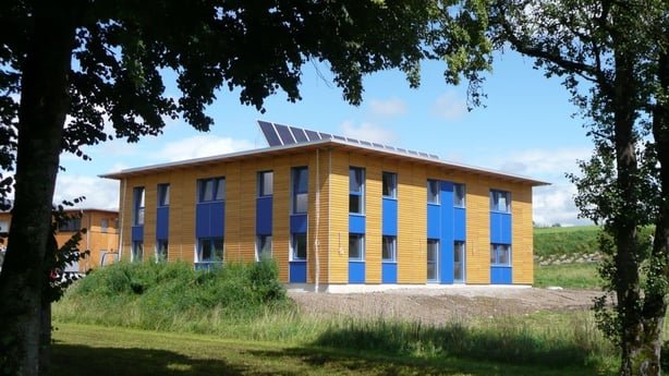 Außenansicht des vollsolar beheizten Bürogebäudes der FA. Selmer in Köstendorf. Das moderne Holzgebäude mit blauen Fenstern hat eine Solaranlage auf dem Dach