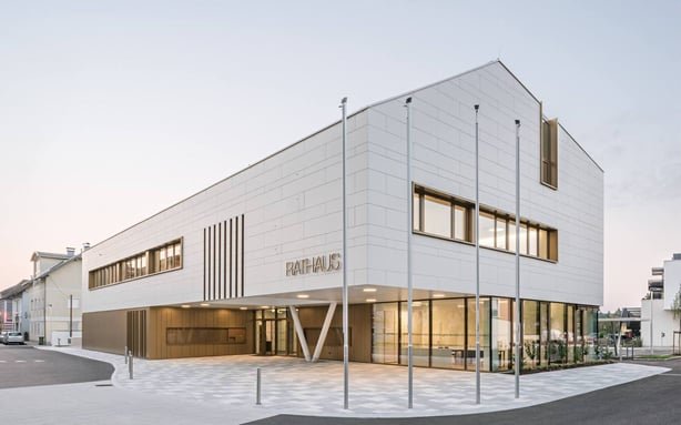 Außenansicht des neuen Rathauses in Oberndorf. Das moderne, weiße Gebäude mit offener Glasfassade ist ein zukunftsorientiertes, vollsolar beheiztes Bürgerzentrum